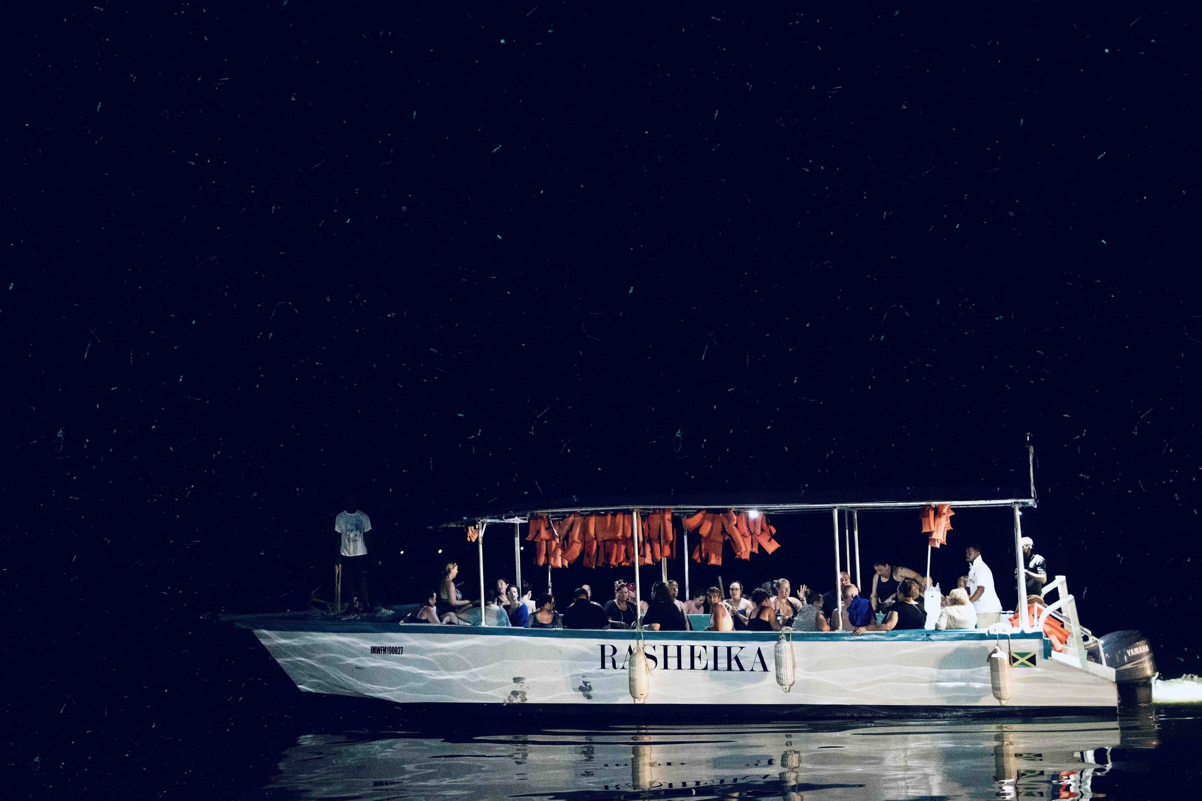 A tour boat lit against the dark water of the luminous lagoon